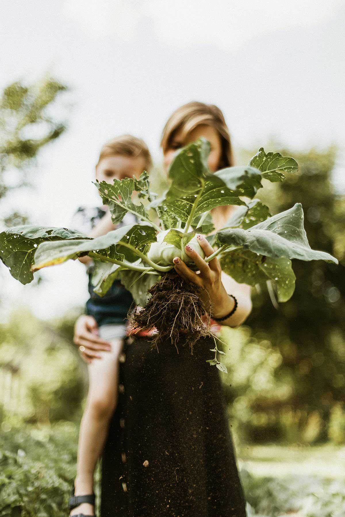 A parent and child holding a freshly harvested plant